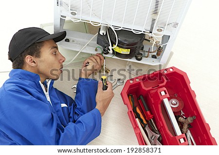 Repairman makes refrigerator appliance maintenance works