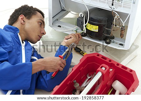 Repairman makes refrigerator appliance troubleshooting and maintenance works
