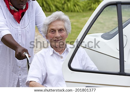 Caregiver helping disabled lady get into the car