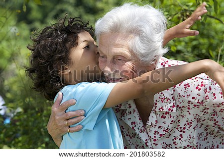 Portrait of grand son hugging and embracing  happy grandmother in the  garden