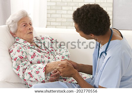 Young mulatto male doctor caring about a very old female patient