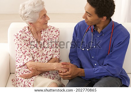 Doctor or care giver holding elderly lady\'s hands.