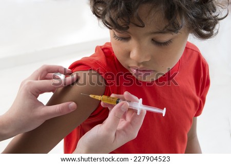 little boy looking at his arm, while receiving vaccine