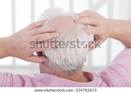man uses both hands to scratch his head with a beginning of baldness