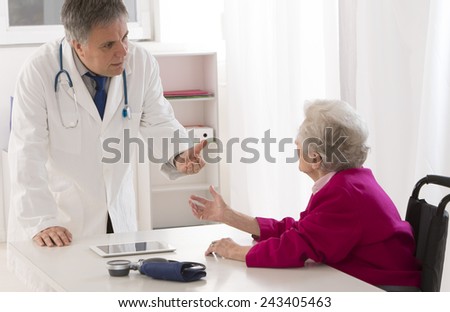 Doctor talking to his disabled senior patient at the office