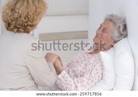 Friendly female doctor comforting a senior patient at hospital or retirement house