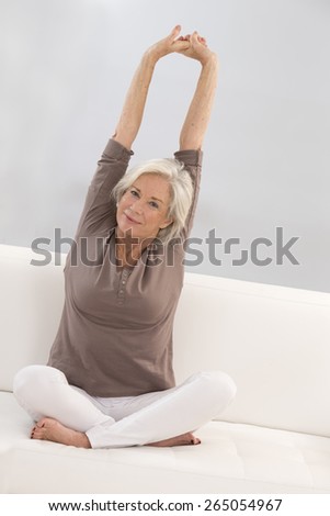 beautiful senior woman relaxing at home in her bed arm  up and stretching
