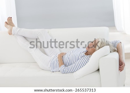 Smart senior  woman relaxing at home  legs lifted on the sofa -flexible, sporty