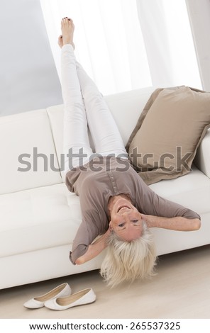 Elegant Senior woman relaxing on a sofa with head upside down