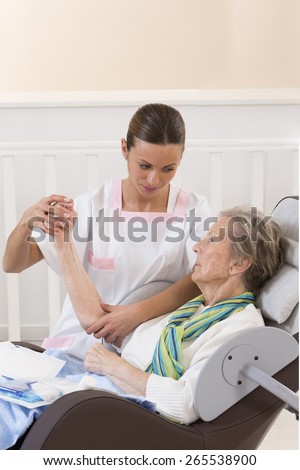 Nurse taking care of senior woman in retirement home bandaging her arm