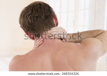 Back view of young man holding neck in pain