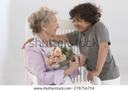 Little boy offering flowers to his grandmother