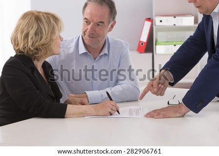 Senior couple writing signature under contract after financial consultation