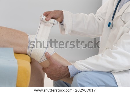 Closed view of a doctor bandaging female patient knee