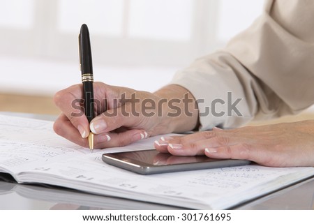 Business woman hand with pen make write notes in notebook and mobile smart phone.