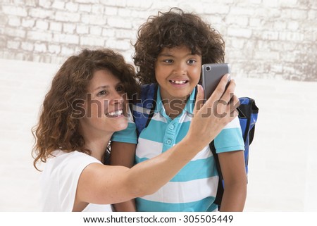 mother and son are doing selfie by mobile phone before first day of school