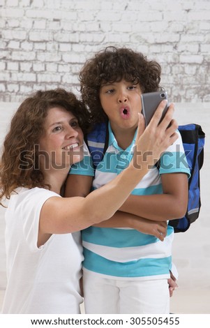 mother and son are doing selfie by mobile phone before first day of school