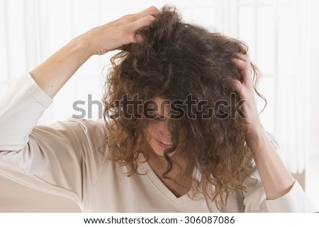 Woman suffering from an headache itching her head