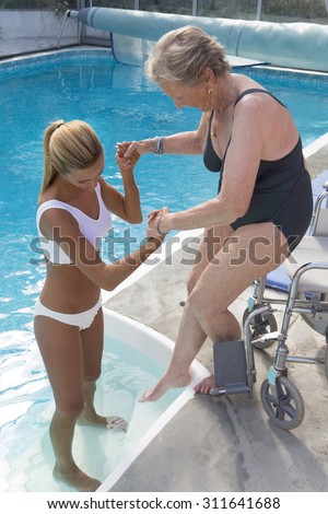 Disabled senior woman with therapist for aqua-gym reeducation
