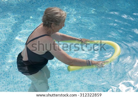 senior woman  doing aqua fitness  with swim noodles