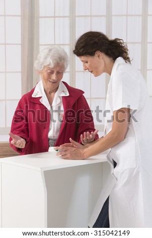 female chemist explaining product details to senior customer in pharmacy