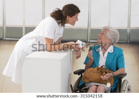 female chemist explaining product details to senior customer in pharmacy