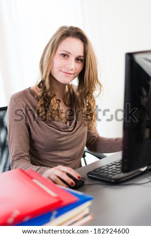 young female student doing homework with computer and cell phone