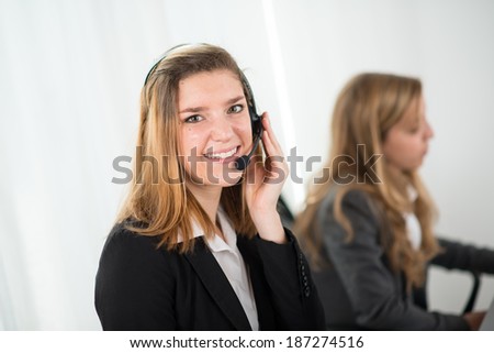 cheerful young telephone worker with co-worker behind