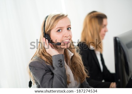 cheerful young telephone worker with co-worker behind