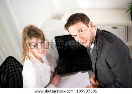 portrait of two business people working together in office with computer