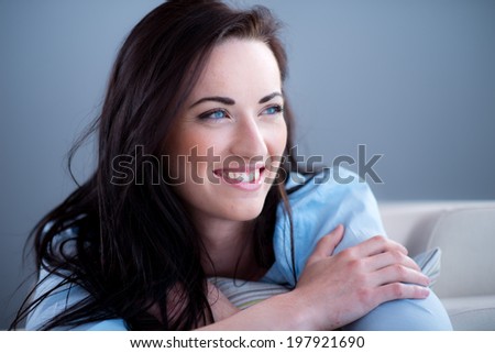 cheerful young brunette lying on her sofa relaxed at home