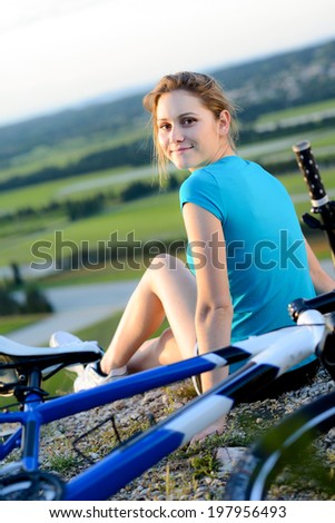 healthy and cheerful young woman riding mountain bike outdoor in the country