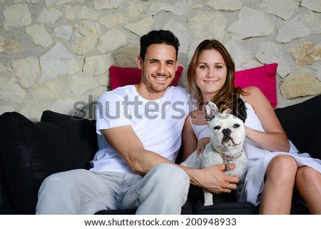 happy and cheerful young couple man woman with pet dog french bulldog sitting outdoor in sofa