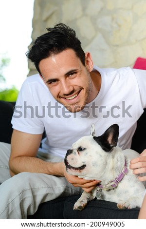 handsome young man with his dog pet french bulldog sitting outdoor in sofa