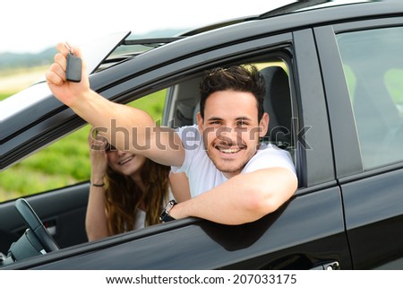 happy and cheerful young couple driving new car during holiday trip in summertime in countryside