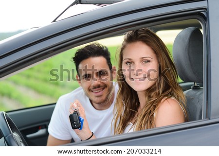 happy and cheerful young couple driving new car during holiday trip in summertime in countryside