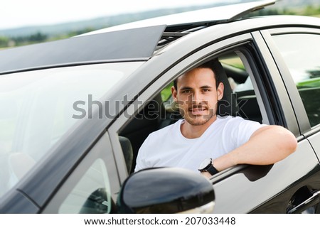 happy handsome young man driving his new car in countryside summer vacation