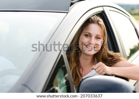 happy cheerful young woman driving her brand new car with new drivers license