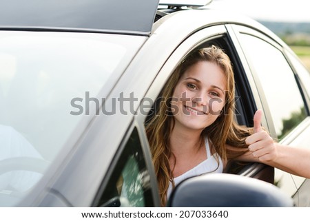 happy cheerful young woman driving her brand new car with new drivers license