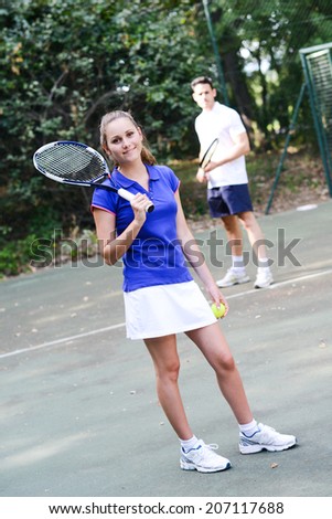 cheerful young woman playing tennis double with boyfriend outdoor summer