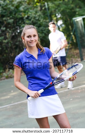 cheerful young woman playing tennis double with boyfriend outdoor summer