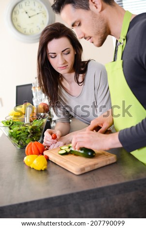 happy beautiful young couple preparing organic vegetables salad for lunch together in kitchen for summer party