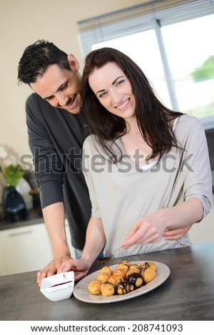 cheerful young couple preparing chocolate dessert in their kitchen at home