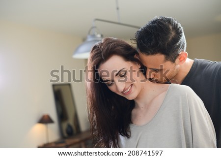 handsome young man kissing beautiful young girlfriend in her neck