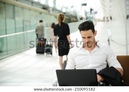 handsome young businessman in public station working on computer in wifi area while waiting for his aircraft or train