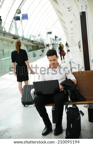 handsome young businessman in public station working on computer in wifi area while waiting for his aircraft or train