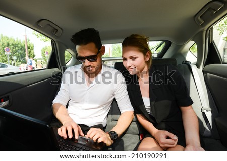 young business people man and woman working together with computer in back seat of taxi cab