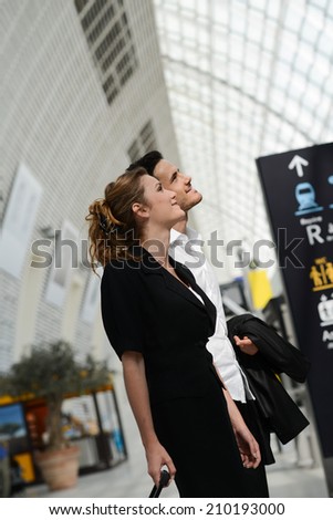 young business travelers man and woman in public transportation station looking for information and schedule