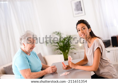 cheerful young girl playing cards with an elderly woman