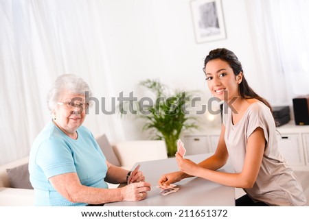 cheerful young girl playing cards with an elderly woman